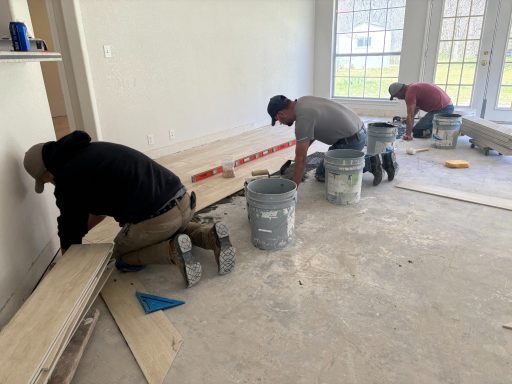 Crew installing hardwood flooring in a large living area during a home renovation.